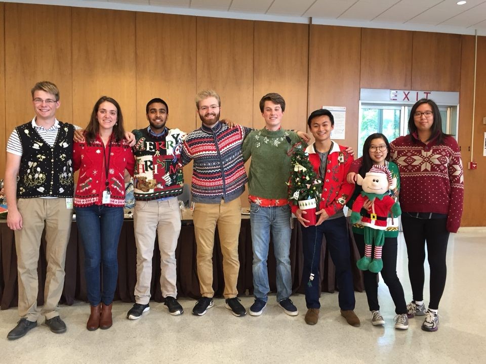 group of young men and women posting in their Christmas and winter-themed sweaters. 