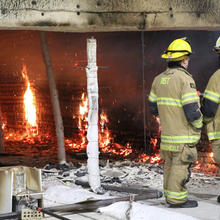 Two firefighters look over the last flames inside a compartment where the flammability of cross-laminated timber buildings is being tested.