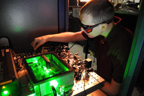 Photo of UC graduate student Matt Kirchner fine-tuning an ultra-stable microwave generator at NIST