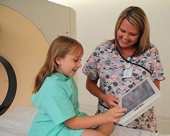 A nurse and young patient share a smile while preparing for a procedure at one of the units serving under the Charleston Area Medical Center Health System