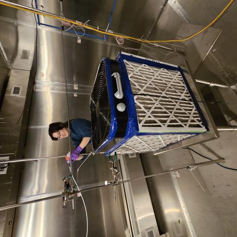 NIST researcher setting up air cleaner experiments in large stainless steel environmental chamber
