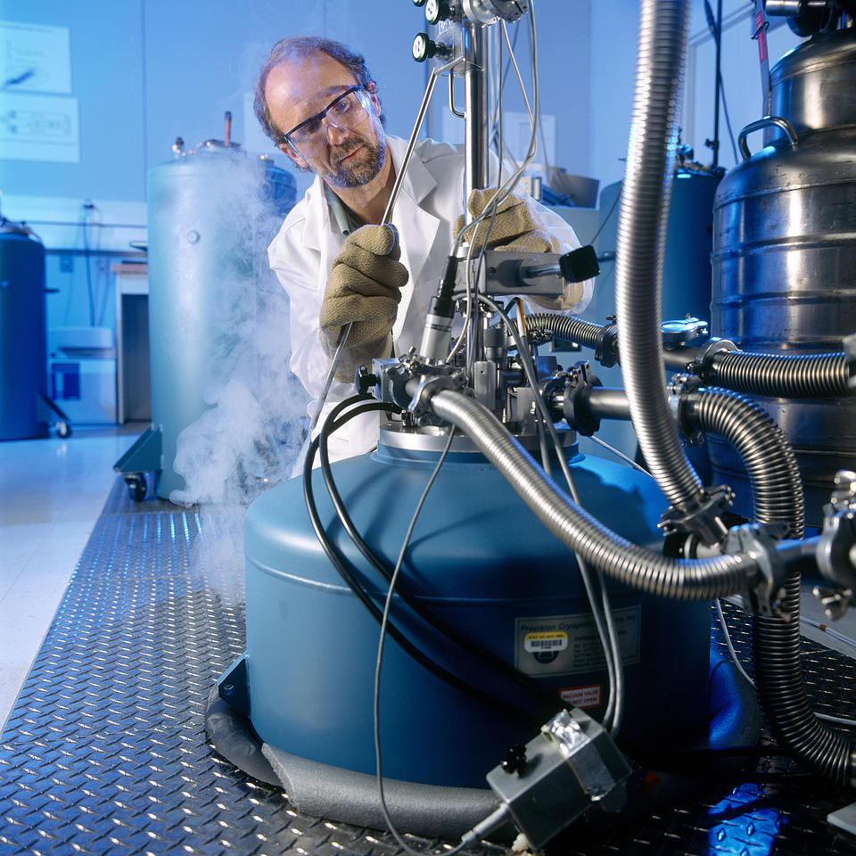Photo of NIST physicist filling cryogenic chamber with liquid nitrogen