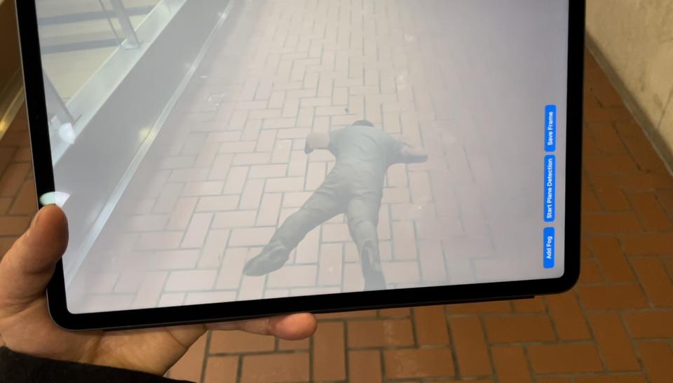 iPad using augmented reality overlay to show an injured person on the floor. 