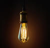 An old-fashioned Edison lightbulb hangs from a wire.