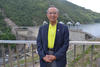 Jeffrey Fong在俯瞰混凝土大坝的栏杆前微笑。 