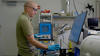 托马斯·福布斯戴着安全眼镜，看着实验室里一台设备上的屏幕。 