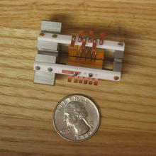 An ion trap sitting next to a quarter to show their similar size