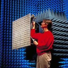 A scientist stands near an antenna in the anechoic chamber