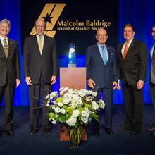 Middle: Baldrige Award on a podium. Left: two men in suits. Right: three men in suites