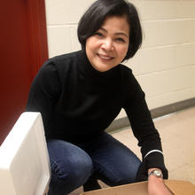 A woman is crouched over an insulated box full of milk samples.