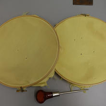 Two round discs. Right one has four holes made with an awl. Left one has two holes.