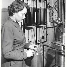 A woman stands next to a system of connected tanks