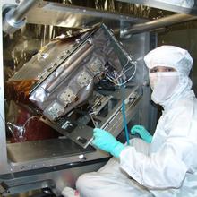 Person in a clean suit places a detector package in a scientific instrument