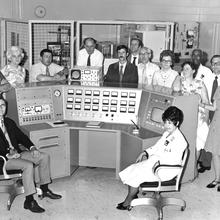 14 individuals sitting in front of scientific equipment