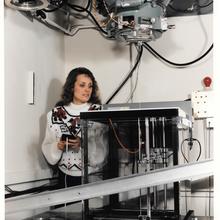 A woman adjusts a scientific device like a large box with overhead components