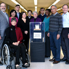The NIST Biometrics Usability team poses next to the fingerprint scanner angle manipulation device