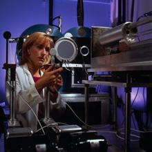 A woman in a lab coat adjusts a piece of scientific equipment
