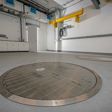 A large white room with circular metal grates in the floor.