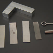 Several rectangular pieces of flat metal, a fake key and a rectangular "gun shaped" piece of metal are arranged on a table.