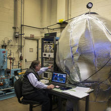 Photo of NIST scientist with the big blue ball covered in thermal insulation.