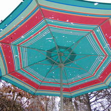 Blue and red patio umbrella has many small holes.