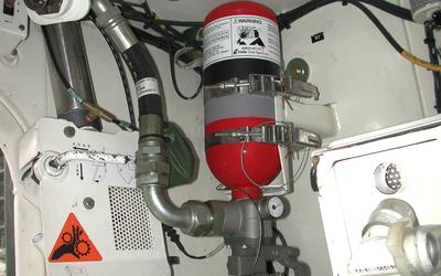 Red fire extinguisher is attached to pipes and hoses inside a vehicle.