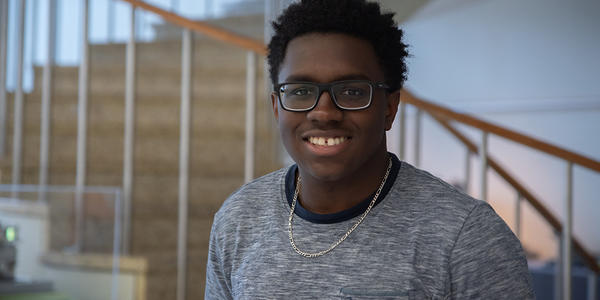 Miles Walker poses smiling in front of the spiral staircase in the NIST library. 