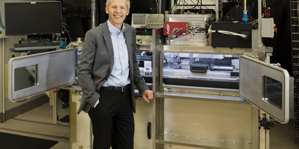 NIST Chief Metrologist Jim Olthoff stands in front of equipment in a lab. 