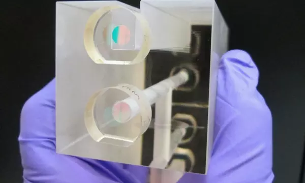 A NIST researcher holds a fixed length optical cavity (FLOC), a structure that enables highly accurate, quantum-based measurements of  pressure.