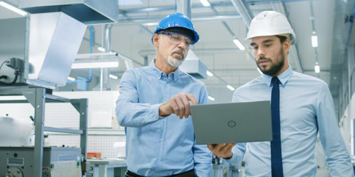 men looking at a laptop in a digital manufacturing facility