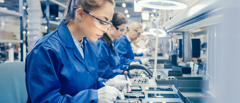 Woman Electronics Factory Worker in Blue Work Coat and Protective Glasses Assembling Smartphones