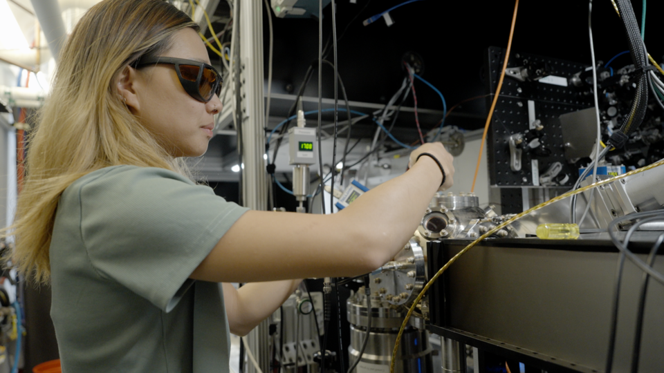 Sun Park wears safety glasses as she adjusts wiring and equipment in the lab. 