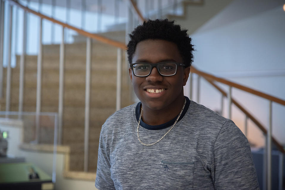 Miles Walker poses smiling in front of the spiral staircase in the NIST library.