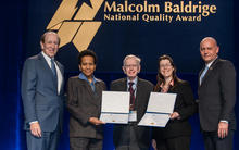Curt W. Reimann is pictured on stage in between the first two scholarship recipients.