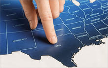 Person pointing finger on the state of texas on U.S. map.