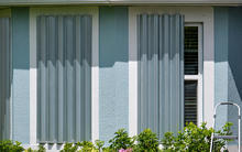 A home with hurricane shutters next to a ladder.