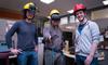 Three individuals wearing firefighter helmets. One individual wears a virtual reality headset.