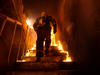 A firefighter walks up the steps of a burning building