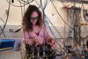 Esther Baumann leans over a lab table, surrounded with wires and scientific equipment.