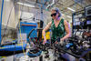 Alejandra Collopy wears safety glasses as she works the lab. She is surrounded by various pieces of equipment and many hanging wires. 